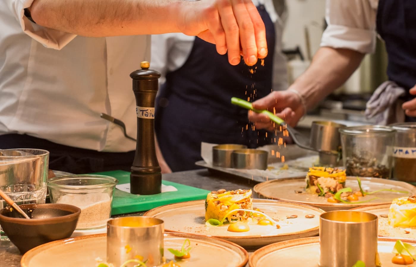 Un chef emplatando bajo las lámparas de calor durante un servicio ocupado en un restaurante.